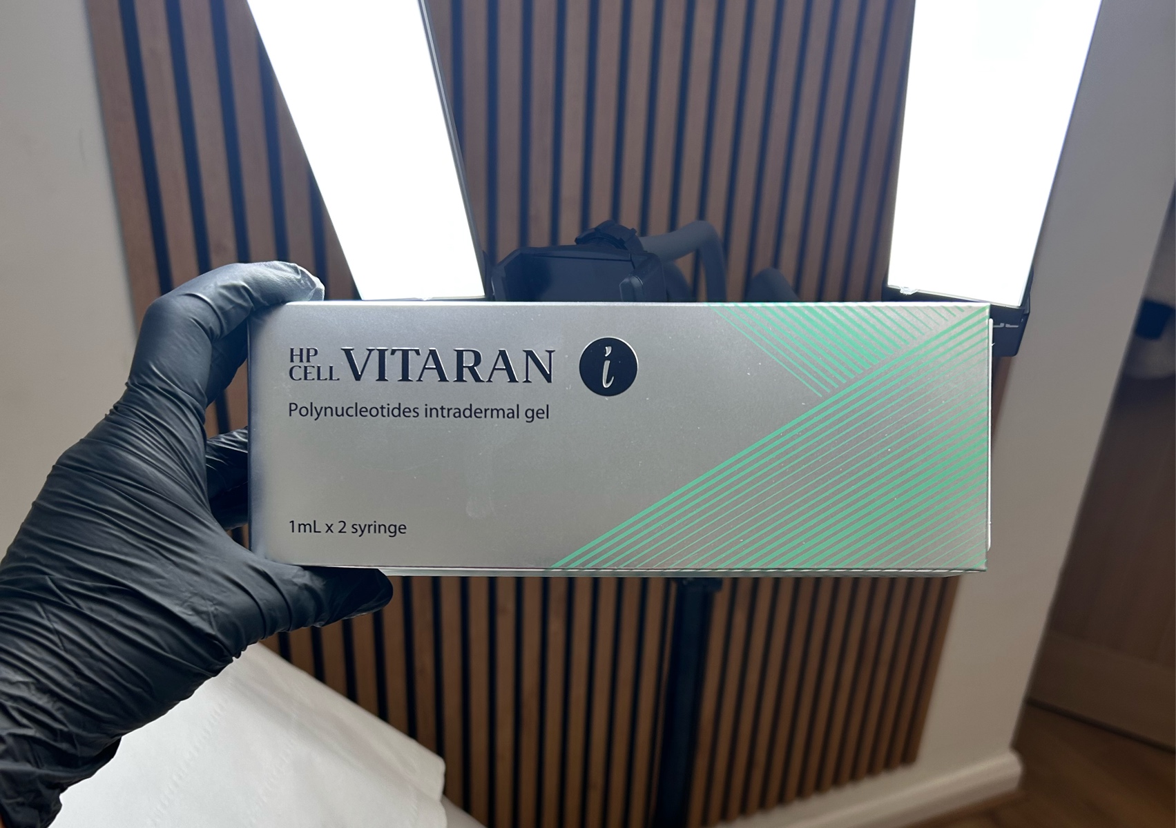 A gloved hand holding a box of VITARAN polynucleotides in the treatment room
